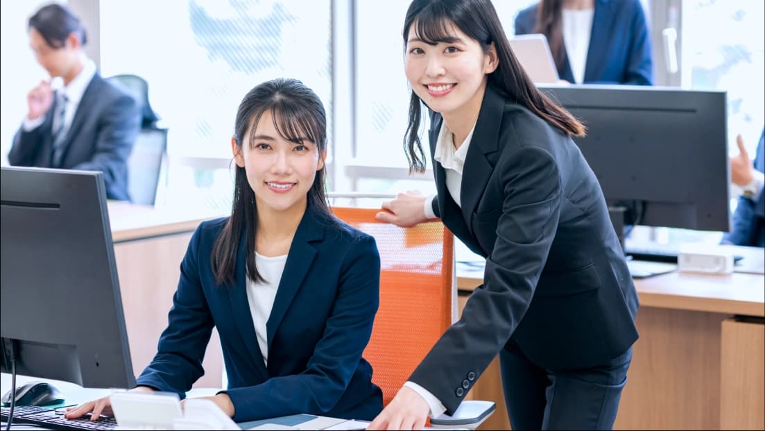 オフィスでPCで作業をする人々の写真